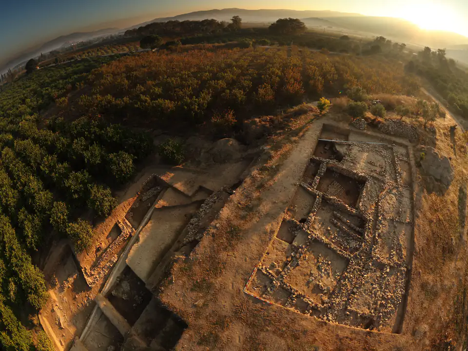 Aerial view of excavation trenches and stone foundations at Çukuriçi Höyük in low golden sunlight
