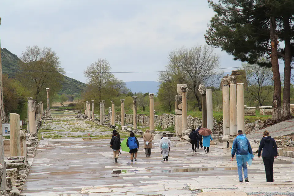 Visitors walk along a broad marble street between rows of columns
