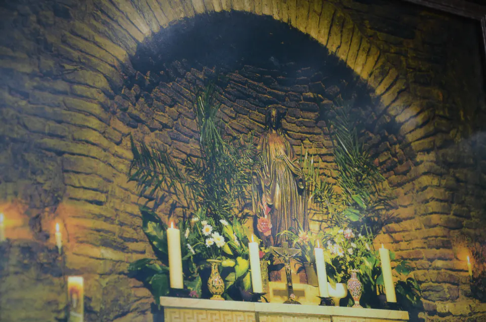 Candle-lit altar with a statue of the Virgin in a vaulted niche