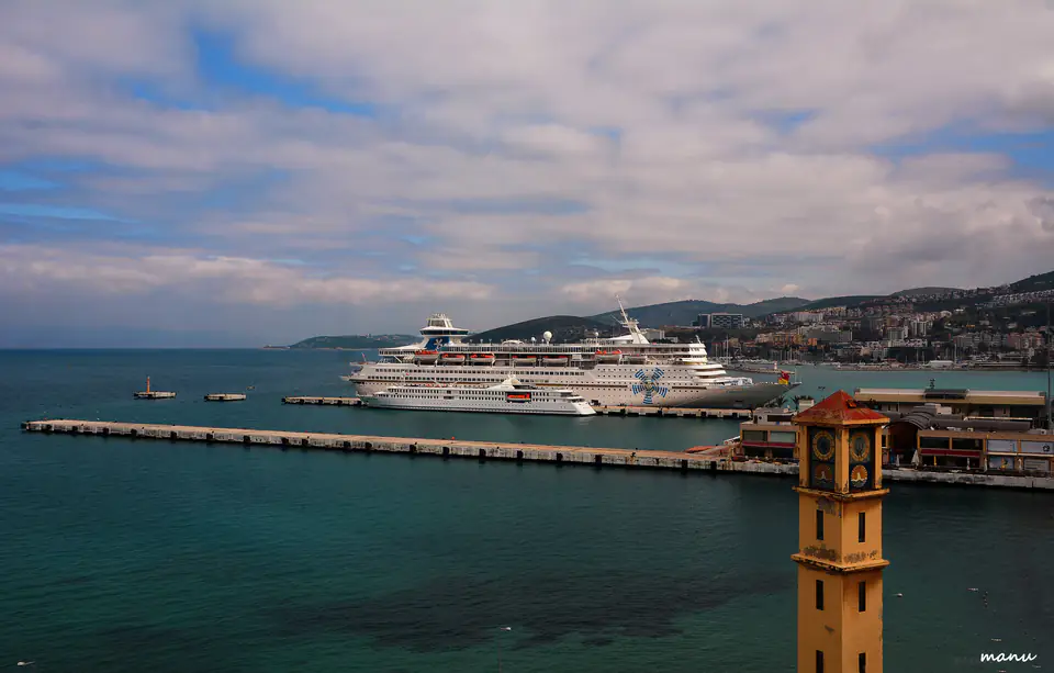 Ön planda limanın saat kulesi, arkasında Kuşadası Limanı’na yanaşmış kruvaziyerler