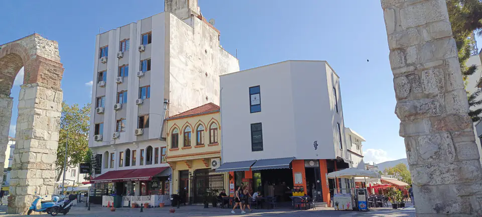 Piloni dell'acquedotto che incorniciano una via di negozi e caffè nel centro di Selçuk