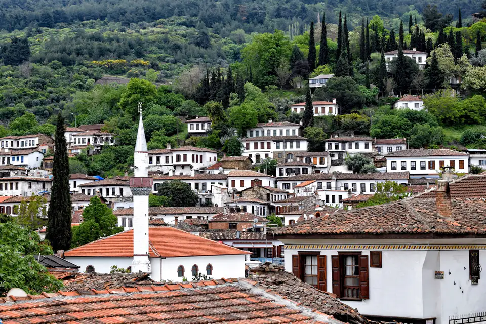 Şirince village, its white-walled, tile-roofed houses on a green hillside, with a minaret among them